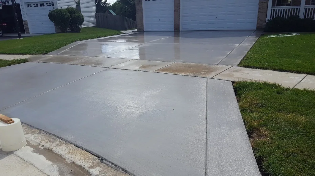 Freshly poured concrete driveway apron meeting the curb and street
