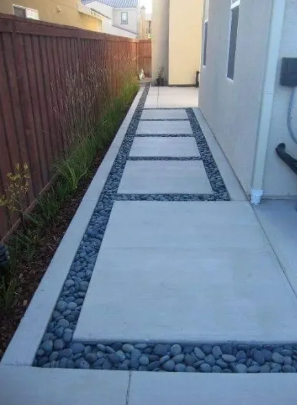 Poured concrete edging bordering a walkway and a landscaped rock bed