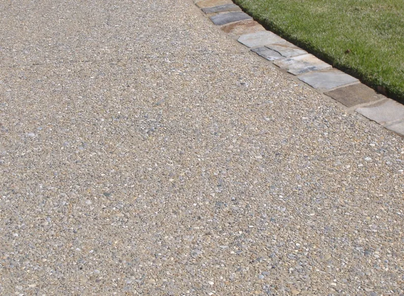 Exposed aggregate concrete driveway with river stone showing through the surface and a paver border