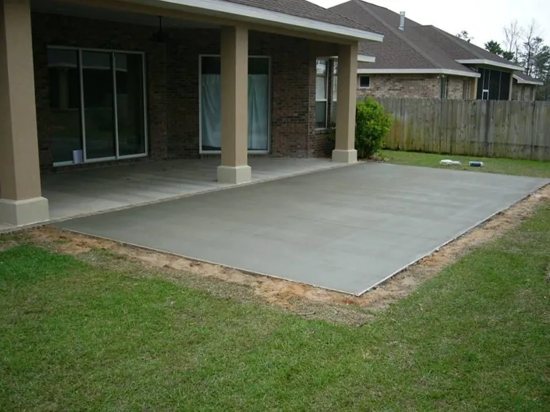 Poured concrete patio slab behind a home, sloped away from the house