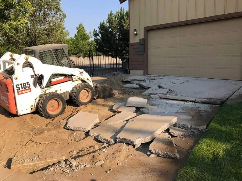 Skid steer breaking out an old concrete driveway during a tear-out and replacement