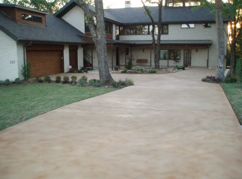 Stained concrete driveway in a warm earth tone curving toward a two-car garage